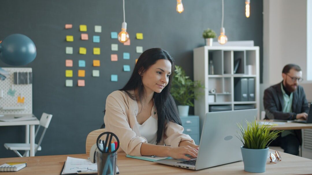 Business professional typing on laptop in modern office environment
